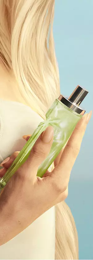 New Starlicious Pistachio Praline in hand asset featuring a model with long blonde hair and blue eyes, wearing a pale yellow dress holding the pistachio praline fragrance bottle