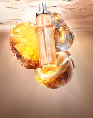 New Starlicious Pineapple Musk still life featuring the slender glass bottle surrounded by its key ingredients: a glowing pineapple slice, a cracked coconut shell, and crystalline musk, all set against a warm, luminous rippling water background.