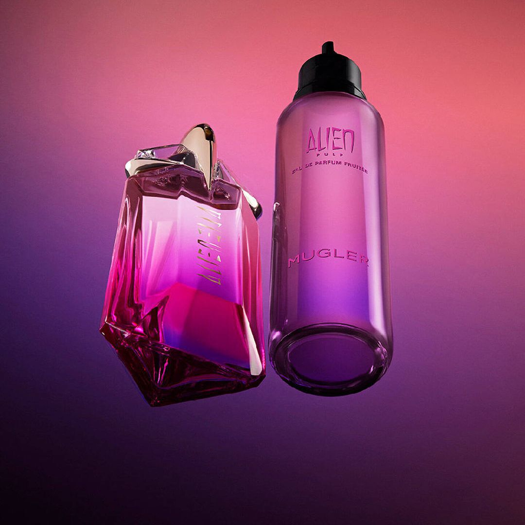 Alien Pulp Eau de Parfum Fruitee star bottle beside pink refill bottle on vibrant pink-purple background.