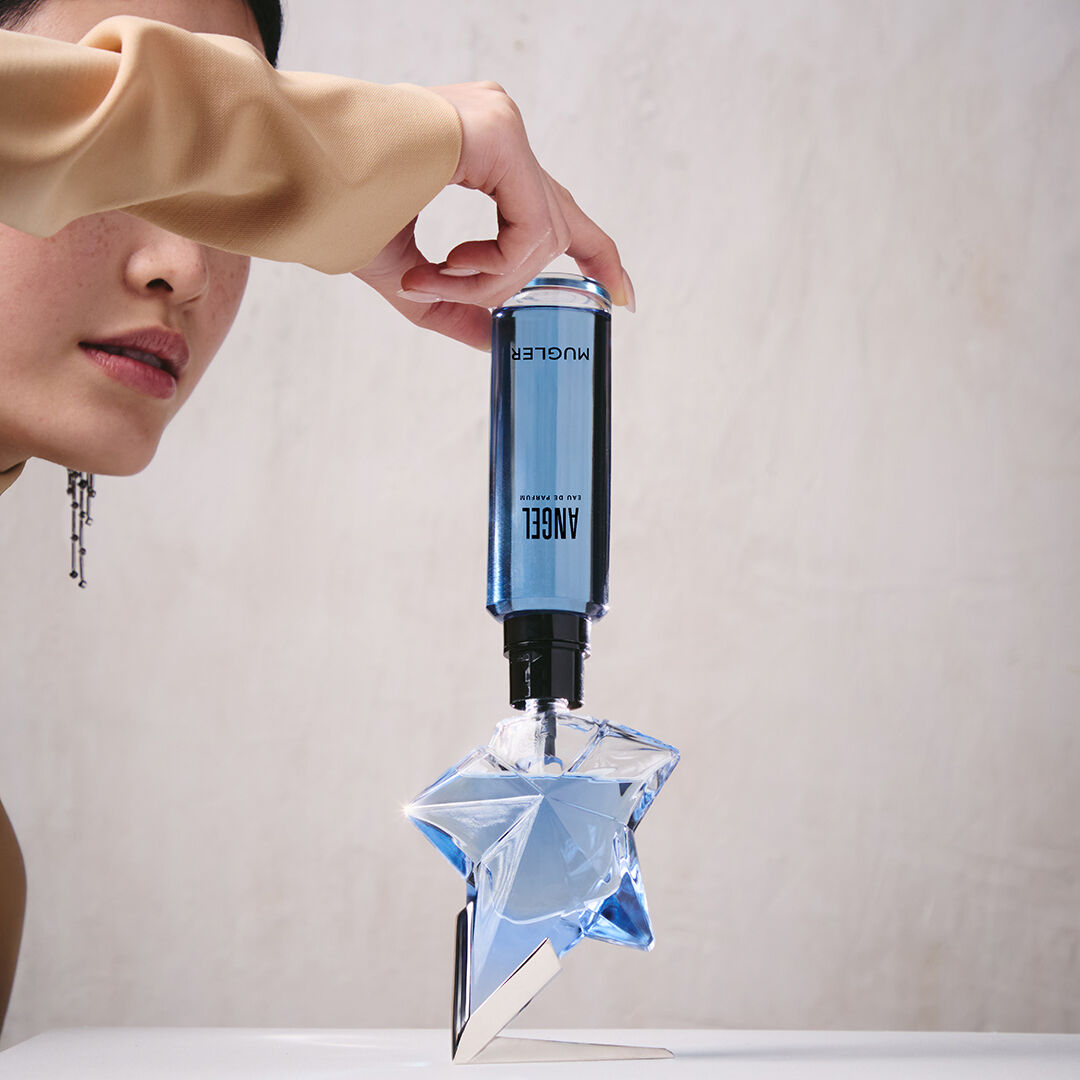 Refilling an Angel Mugler star perfume bottle with a blue refill bottle held upside down​