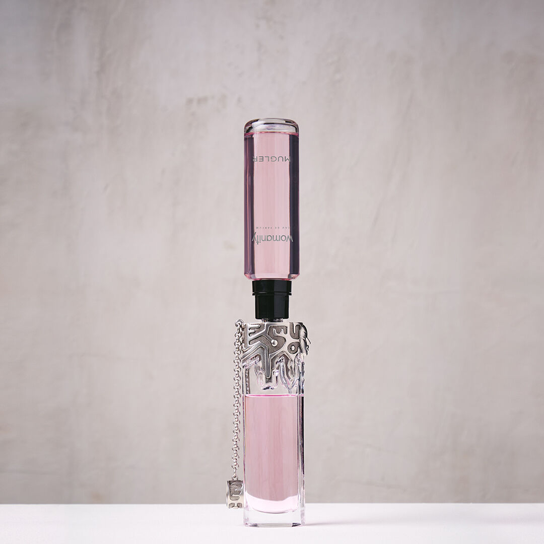 Pink Mugler Womanity refill bottle connected upside down to perfume bottle​