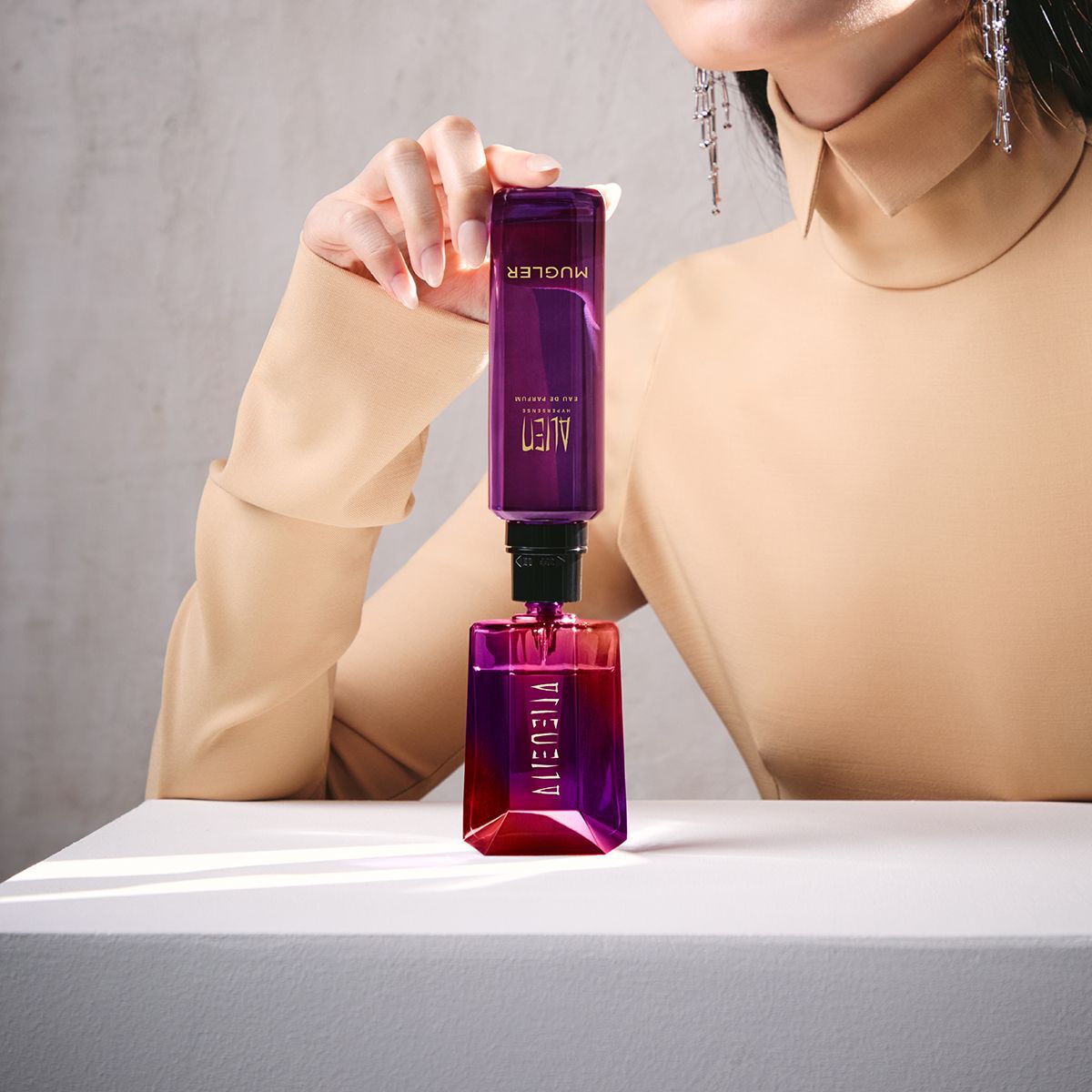 Model refilling Alien bottle from matching purple refill vial