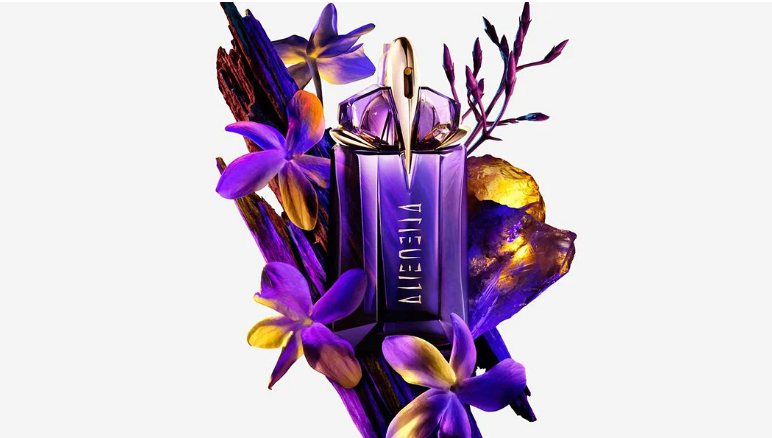 Mugler Alien perfume bottle surrounded by purple flowers and textured wood