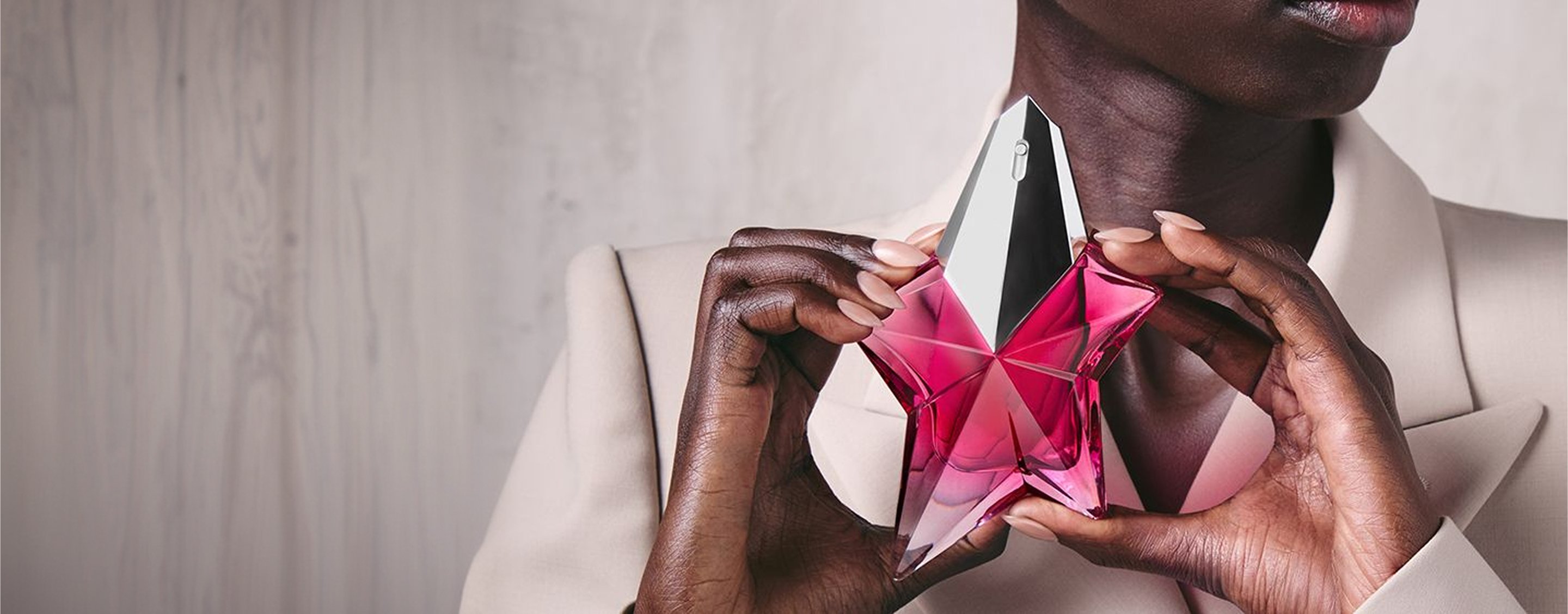 Model holding the Angel by Mugler star-shaped pink crystal fragrance bottle close to her chest