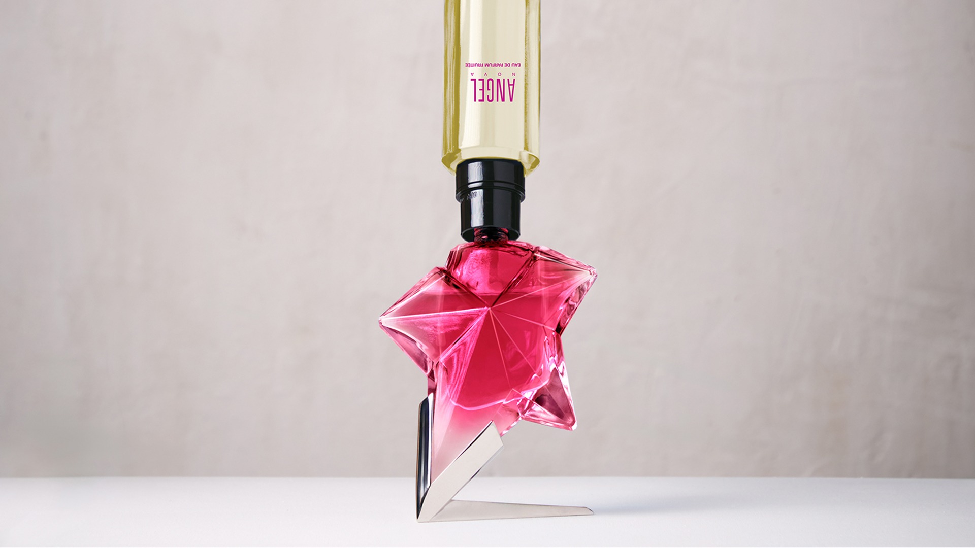 Refilling a pink Angel Nova star perfume bottle with a yellow refill bottle held upside down.