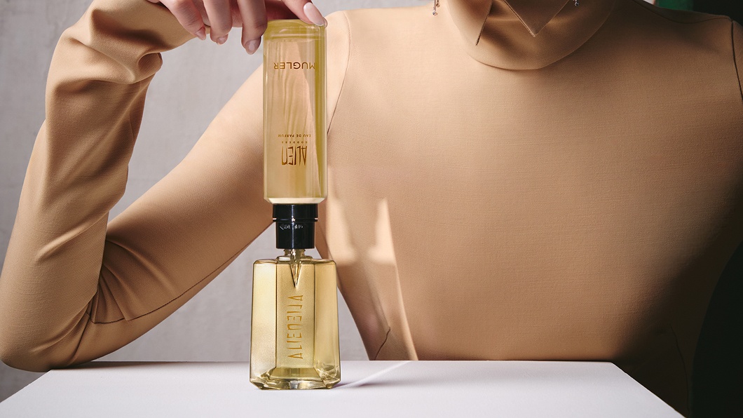 Model refilling an Alien Goddess perfume bottle with a matching refill bottle.