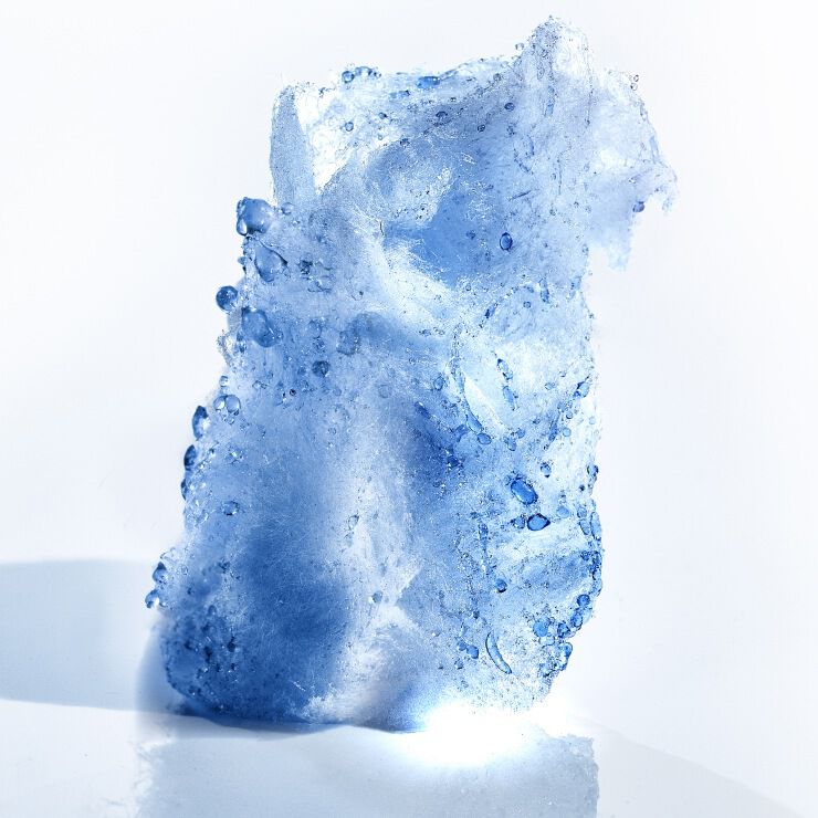 Abstract macro sculpture of a translucent pale blue crystalline form covered in water droplets, evoking aquatic and mineral fragrance ingredients