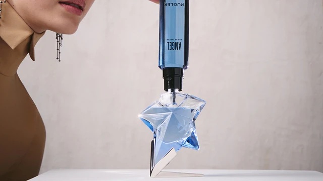 Refilling an Angel Mugler star perfume bottle with a blue refill bottle held upside down