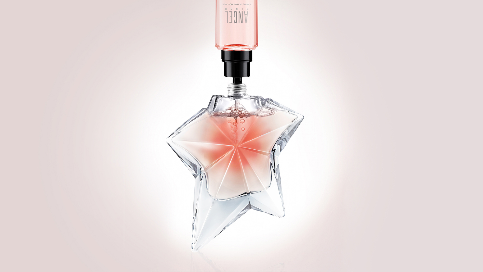 Refill bottle dispensing Mugler Angel Blush perfume into a star-shaped bottle.